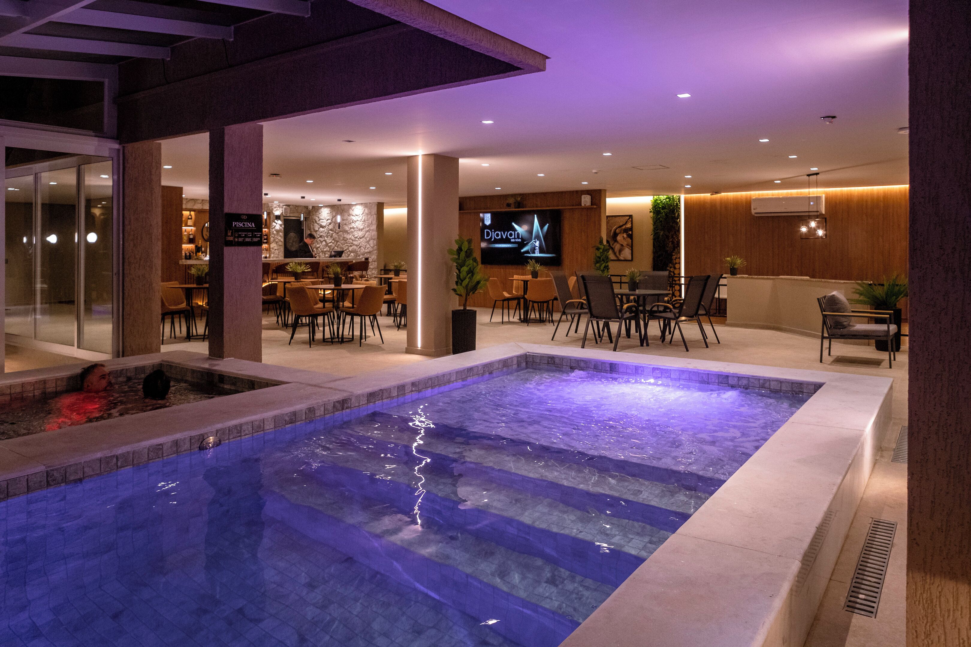 A hotel lobby with a pool, seating areas, and a bar.