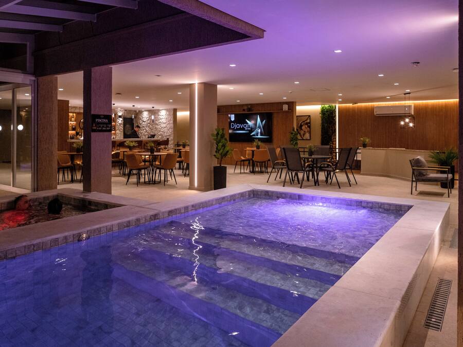 Eine Hotelhalle mit Pool, Sitzbereichen und einer Bar.