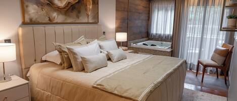 Amplia habitación con una cama grande, un espacio de descanso con una silla, una bañera y un cuadro abstracto de gran tamaño en la pared.
