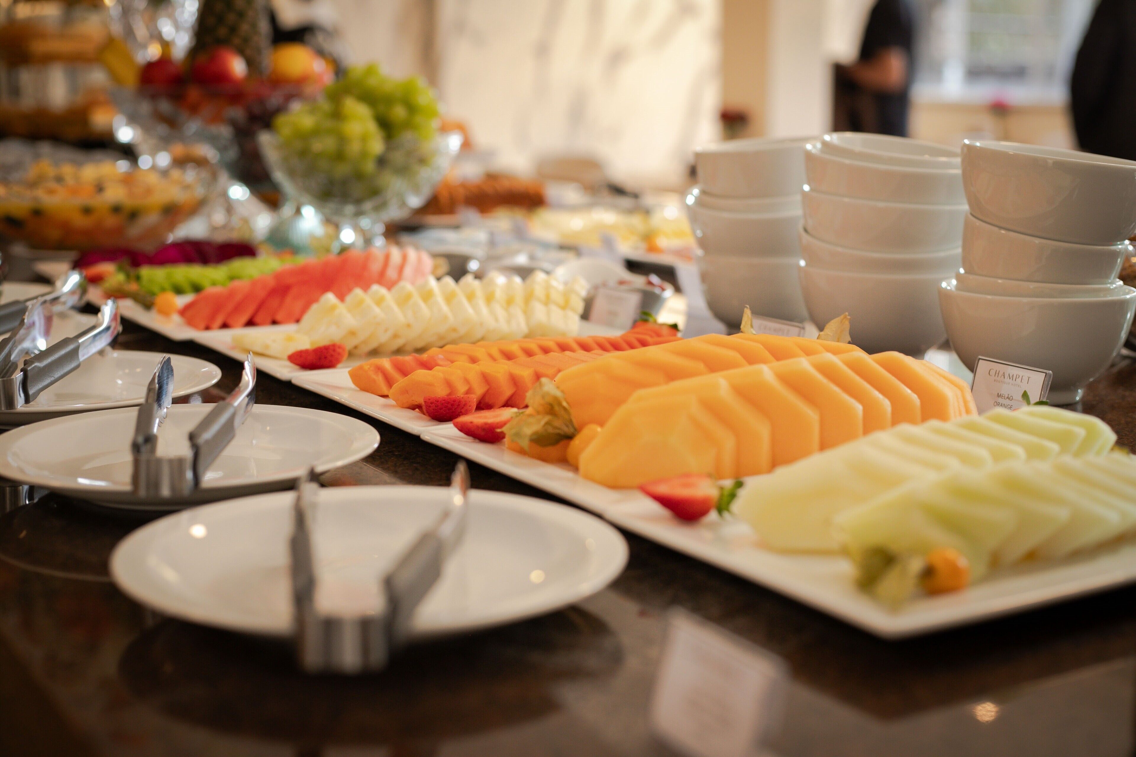 Una mesa de buffet con diversas frutas y verduras, incluyendo sandía, melón y zanahorias.