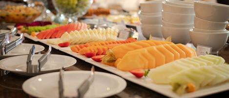 Una mesa de buffet con diversas frutas y verduras, incluyendo sandía, melón y zanahorias.