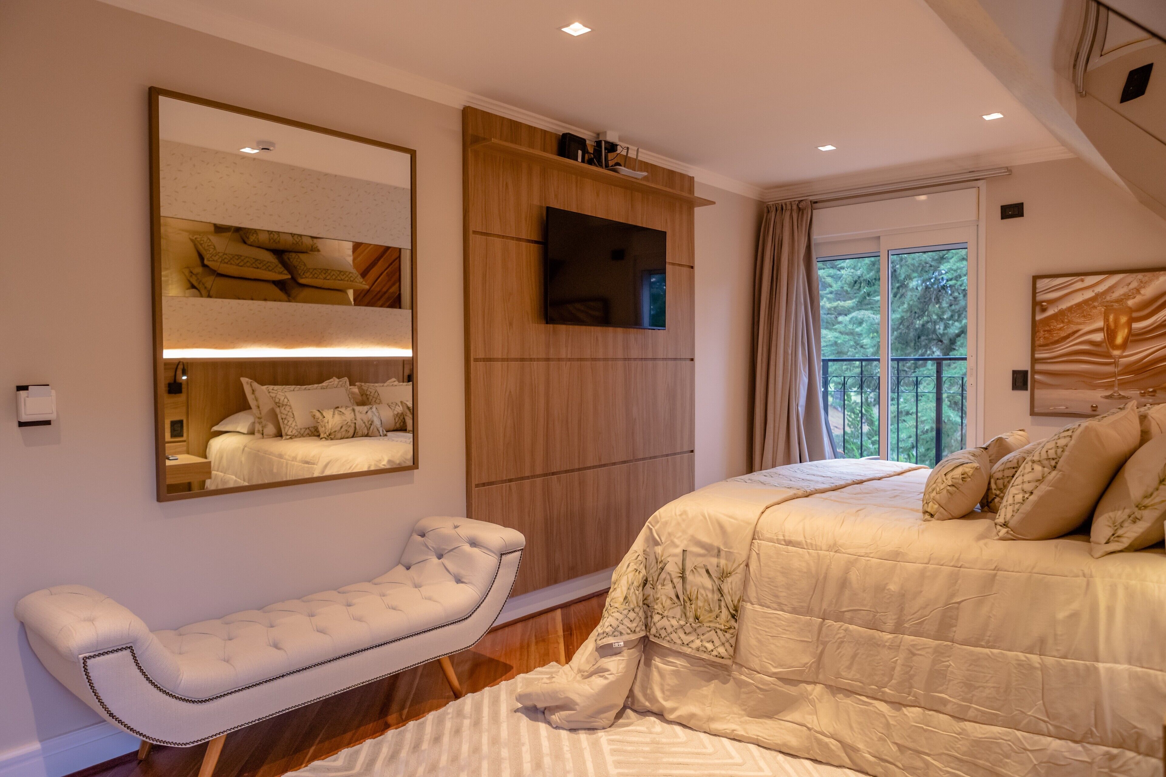 Um quarto com uma cama grande, um banco, uma TV e um guarda-roupa.