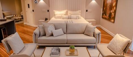 Ein modernes Schlafzimmer mit einem großen Bett, zwei Nachttischen, einem Beistelltisch, einem Sofa und einem Couchtisch.