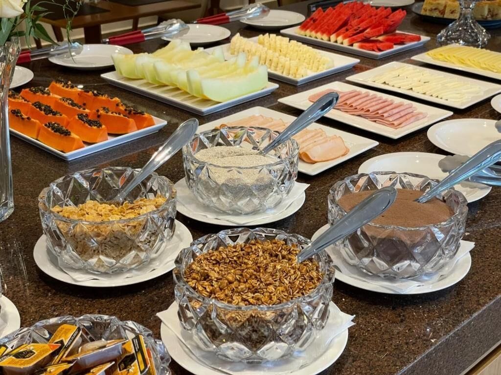 Un bufé con diversos alimentos, entre ellos frutas, quesos y cereales.