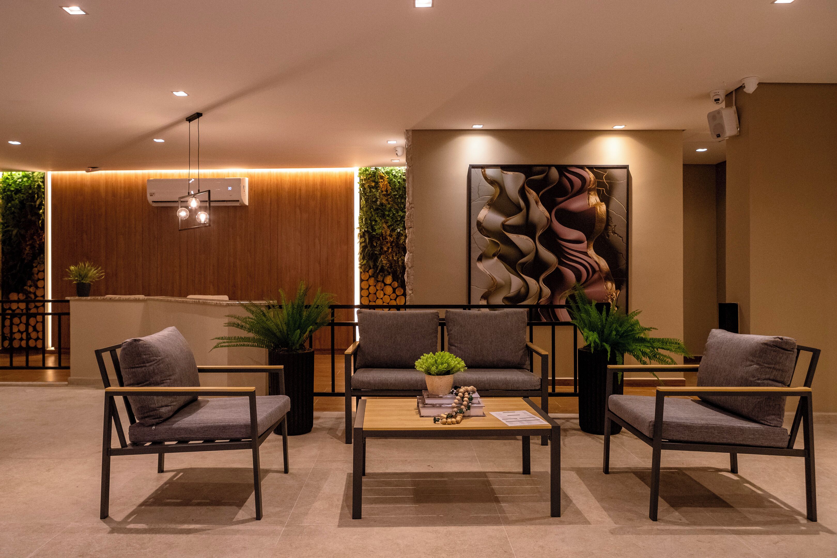 A modern lobby with a sofa, two armchairs, a coffee table, and decorative plants.