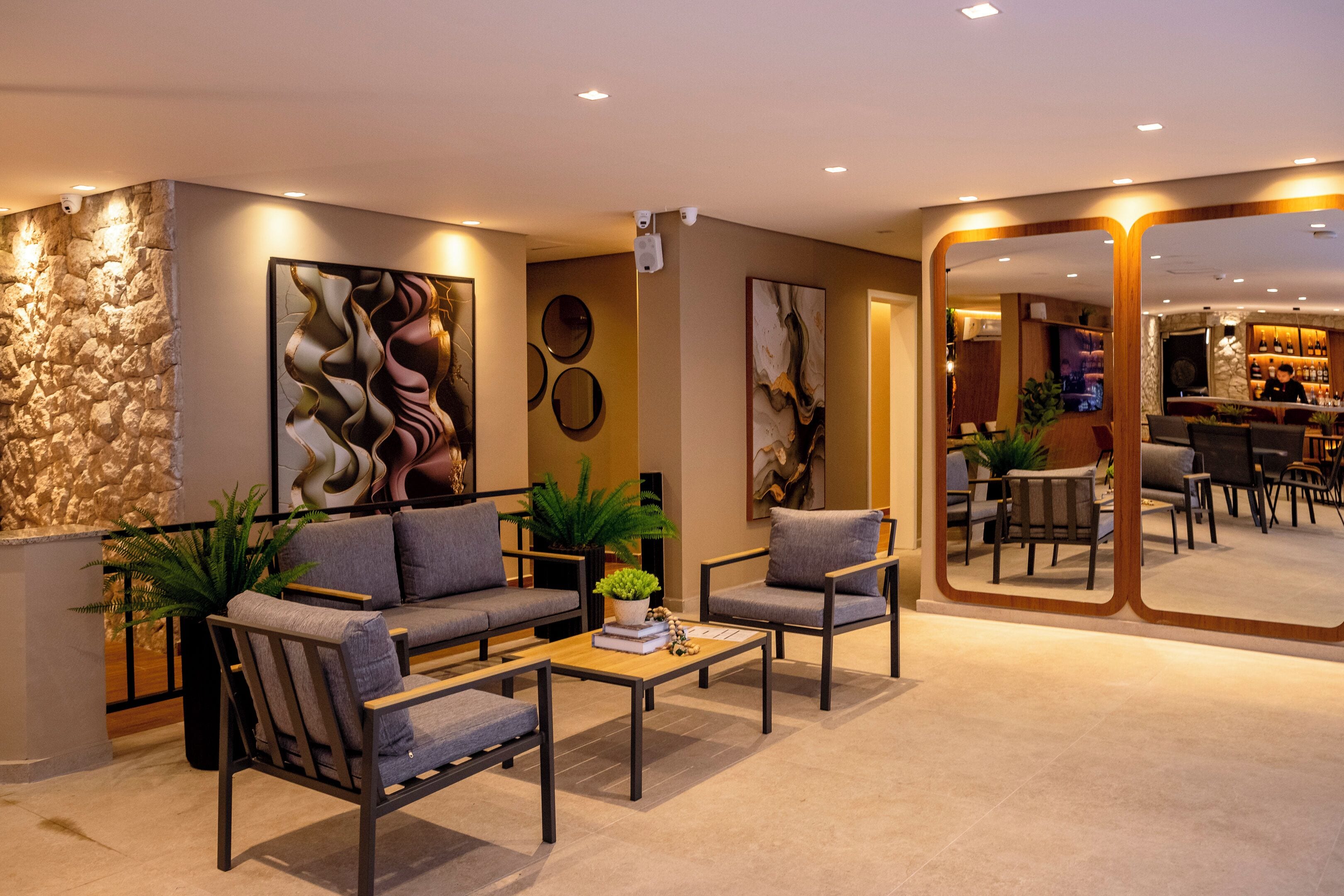 Ein stilvoller Lounge-Bereich mit Sofas, Sesseln, einem Couchtisch und einem großen Spiegel.