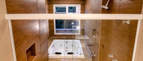 A modern bathroom with a glass-enclosed jacuzzi, wooden walls, and a shower area.