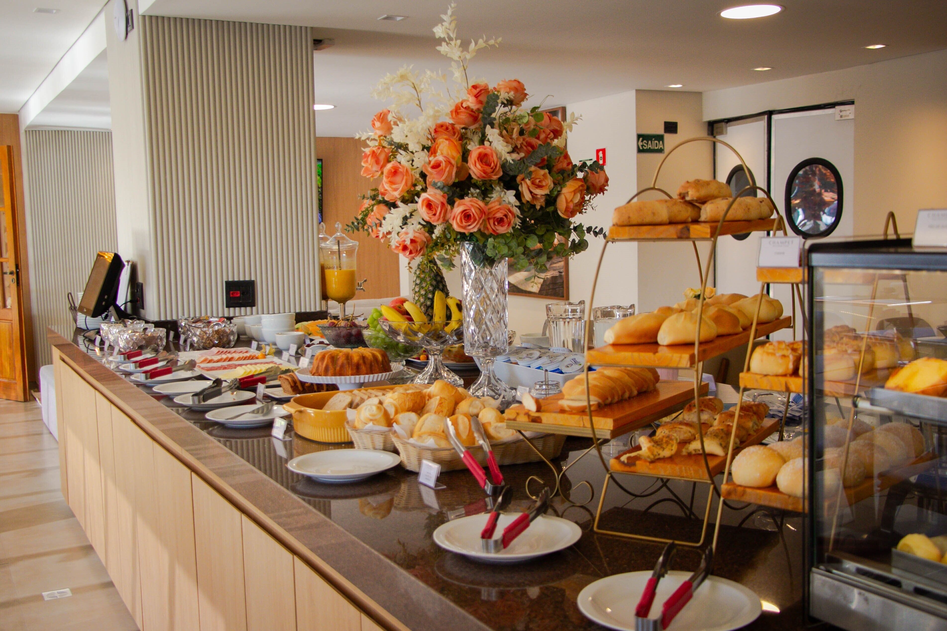 A buffet with various food items, a floral centerpiece, and a clock on the wall.