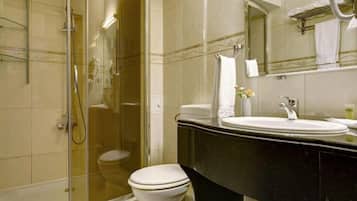 A bathroom with a glass-enclosed shower, a white toilet, and a black vanity with a sink and mirror.