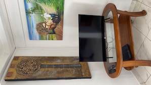 Ein an der Wand befestigter Fernseher, ein Holzregal mit einem dekorativen Gegenstand und ein Gem älde.