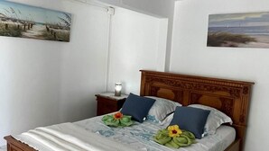 Ein Schlafzimmer mit einem hölzernen Bettgestell, weißer Bettwäsche und einem Bild an der Wand.