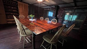 A wooden dining table with chairs, a ceiling fan, and a potted plant. - Peaceful Entire 4 BR 2 BA Cabin with AC, WiFi, Pond  View, Recreational room (Crisfield)