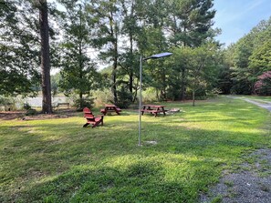 A picnic area with benches and a solar-powered light post. - Peaceful Entire 4 BR 2 BA Cabin with AC, WiFi, Pond  View, Recreational room (Crisfield)