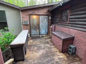 Une terrasse en bois avec un barbecue, un mur en briques et une porte-fenêtre coulissante.