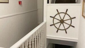 A staircase with white balusters and a ship's wheel decoration on the wall. - Regis Lodge Guesthouse  (Bognor Regis)