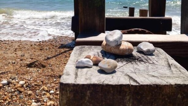 A wooden bench with rocks on a pebbled beach, overlooking the ocean. - Regis Lodge Guesthouse  (Bognor Regis)