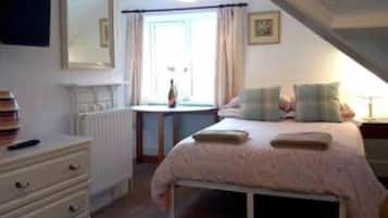 A bedroom with a bed, a dresser, a window with curtains, and a radiator.