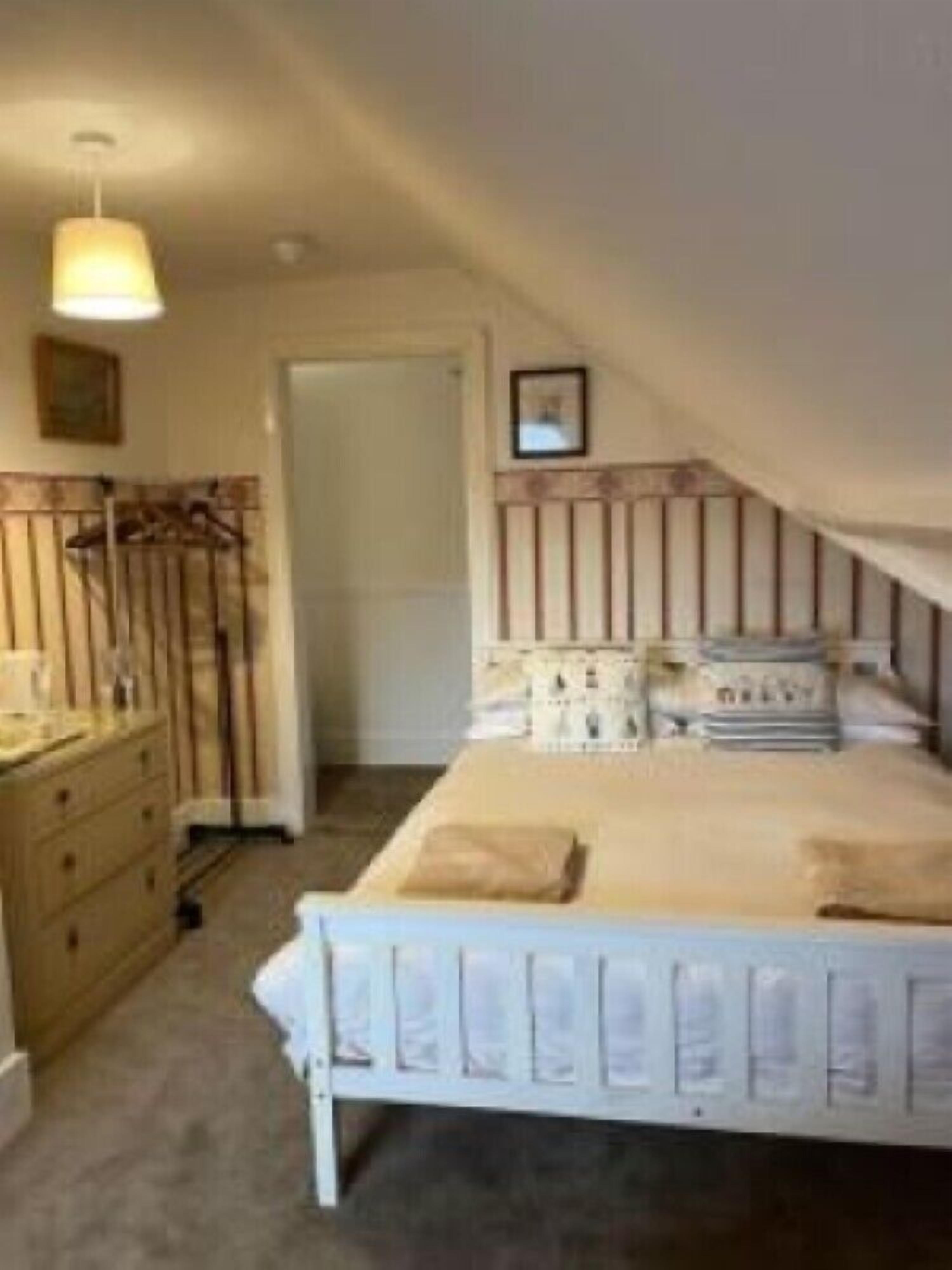 Un dormitorio con una cama individual, un aparador y una lámpara colgante.