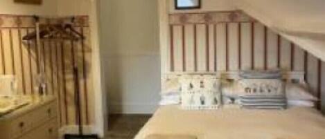 A bedroom with a single bed, a dresser, and a hanging light fixture.