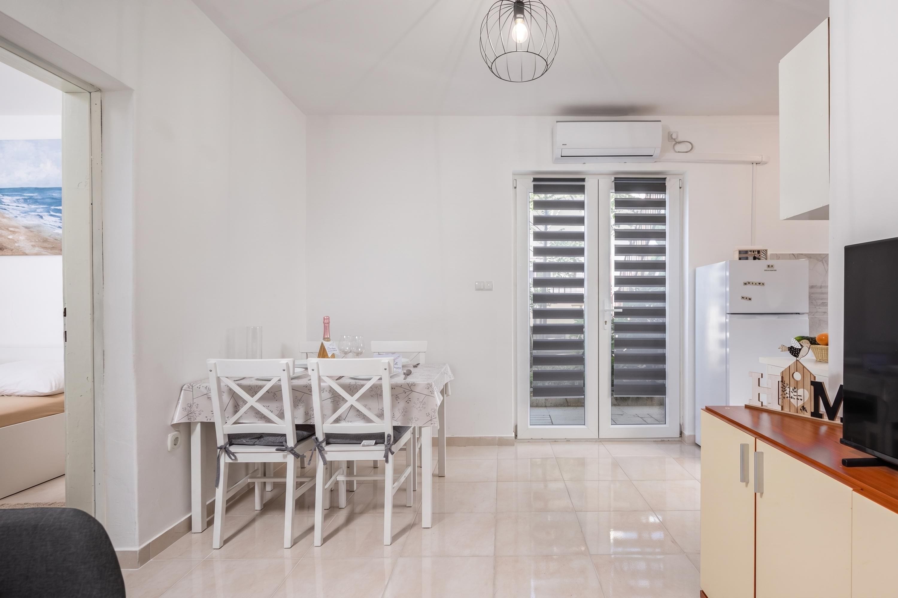 Una cocina moderna con horno empotrado, un comedor con mesa y sillas, y vista al mar a través de un ventanal corredero.
