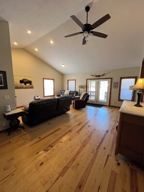 A spacious living room with a ceiling fan, hardwood flooring, a leather sofa, and a dining area with a lamp. - Near Stickney Creek boat launch-2 bedroom, 2 full bath house with private pond. (Craig)