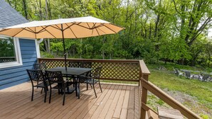 Une terrasse en bois avec une table et des chaises, un parasol et une rambarde en bois.