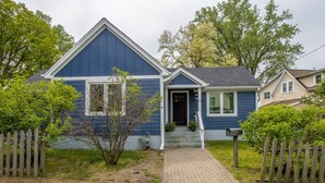 Une maison à deux étages, avec une façade bleue, un porche à l’avant et une boîte aux lettres.