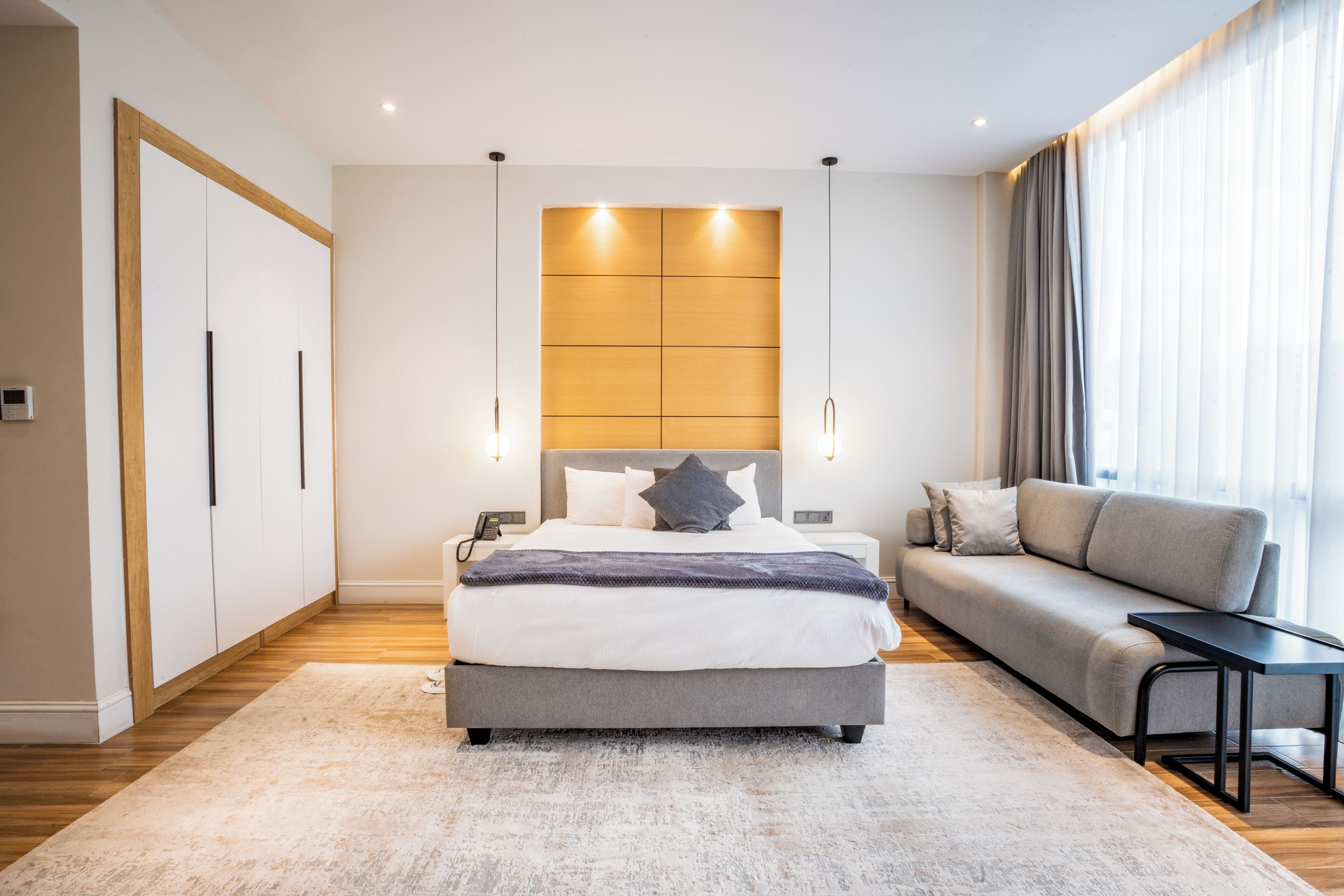 Een moderne slaapkamer met een bed, een bank en een nachtkastje.