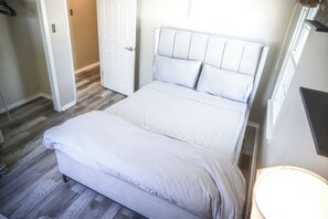 Cozy retreat with a large bed and tufted headboard, featuring multiple pillows and a lamp.