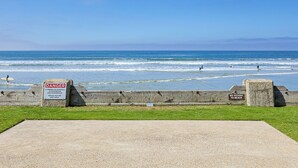 A beach with warning signs, a wooden barrier, and a clear blue sky. - West-Facing ocean views and picturesque sunsets from a private balcony. (Oceanside)