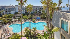 A resort with a large swimming pool surrounded by palm trees and lounge chairs. - West-Facing ocean views and picturesque sunsets from a private balcony. (Oceanside)