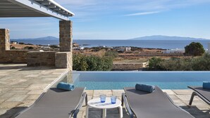 A poolside area with two sun loungers, a small table, and a stone pillar. - Villa louise, sea view, swimming pool, sleeps 12, near Drios (Drios)