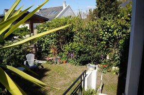 A garden with a white chair, a small table, and various potted plants. - L'Ecrin de l'Océan 80 m de la mer (Le Pouliguen)