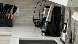 Cuina amb taulell de marbre, un rentaplatets d'acer inoxidable i una cafetera.