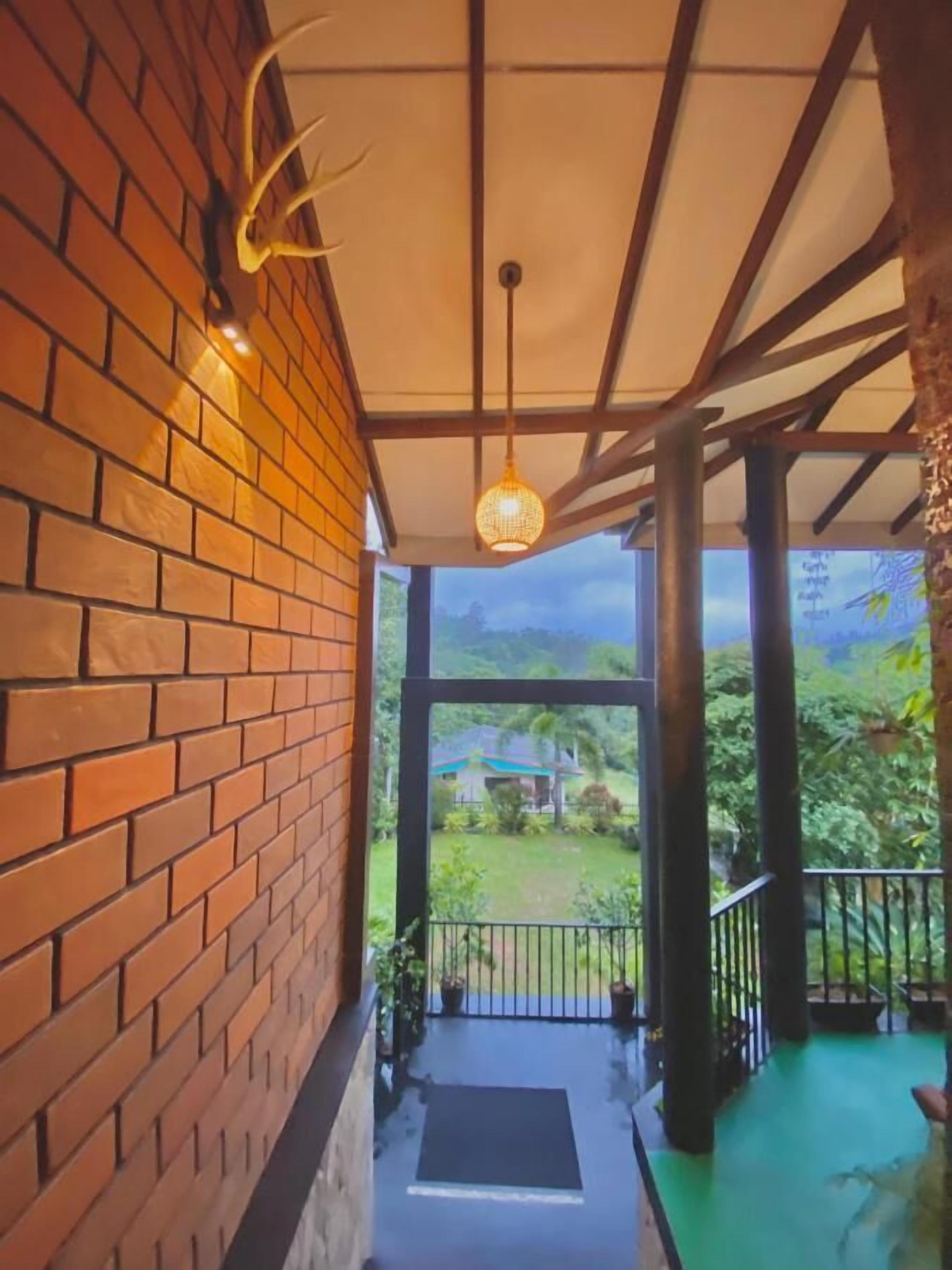 Un pasillo cubierto con un muro de ladrillo, una lámpara colgante y vistas de un paisaje verde.