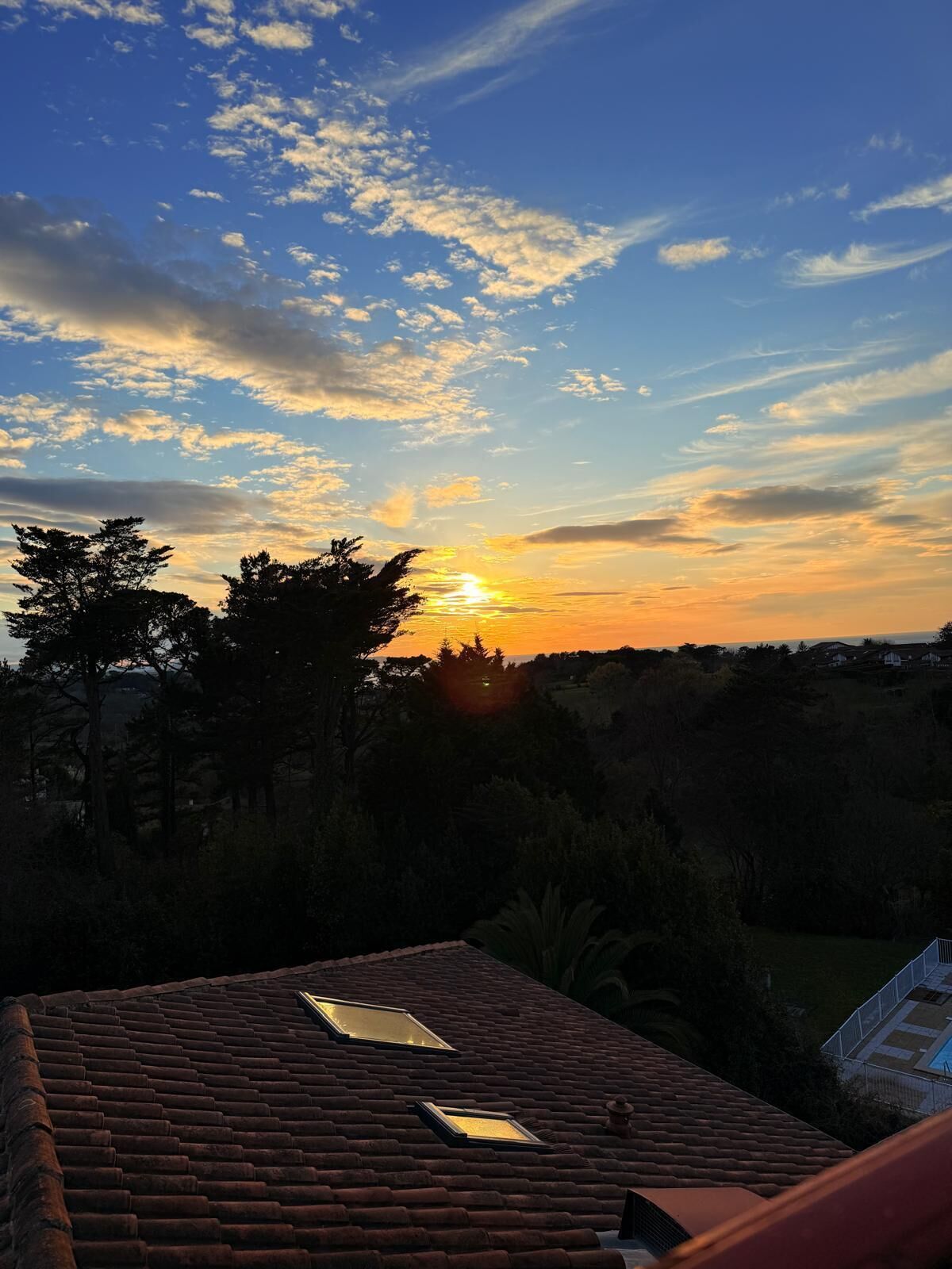 A sunset view from a rooftop with two skylights.