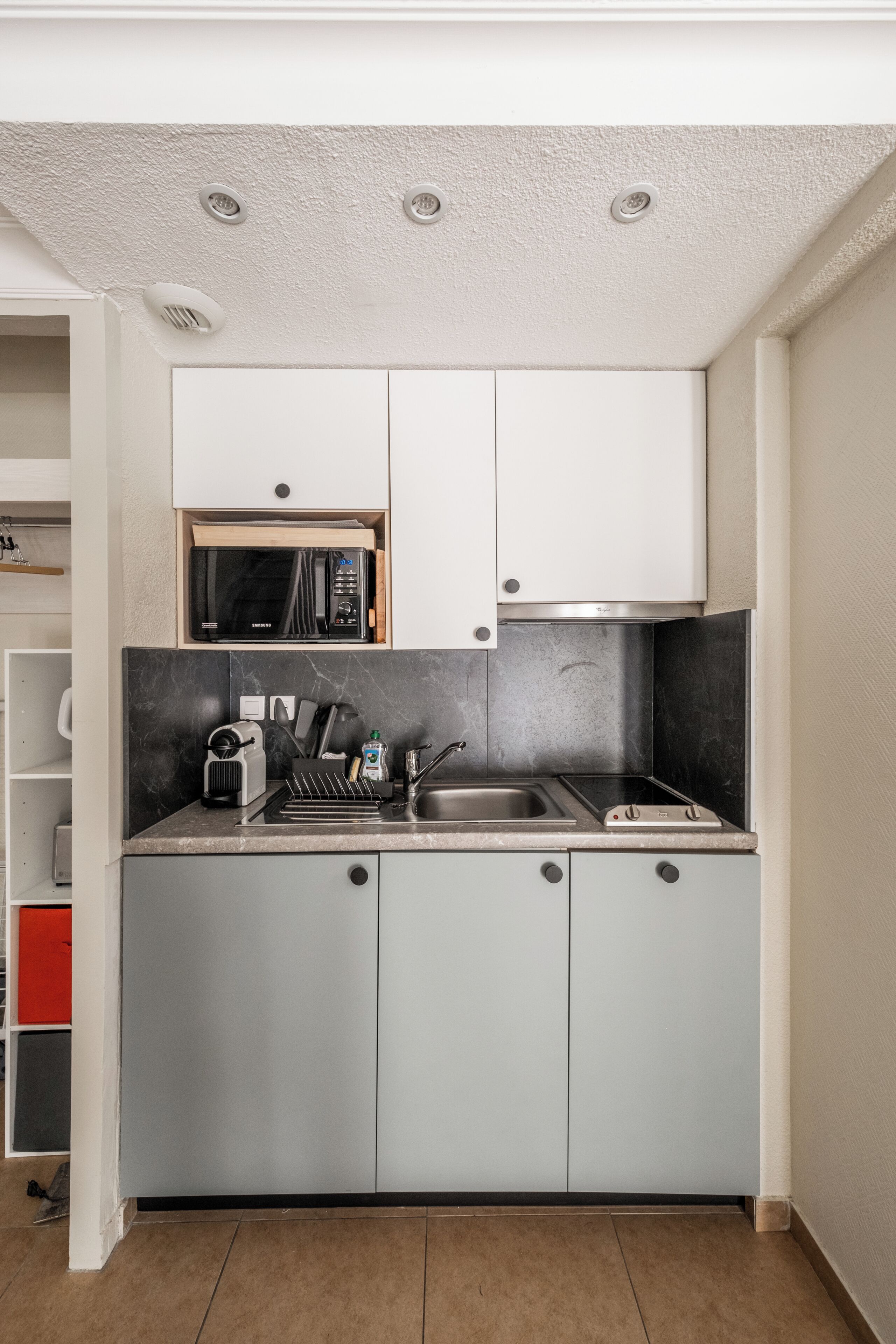 Eine kleine Küche mit weißen Schränken, einer Mikrowelle, einem Spülbecken und einem Toaster.