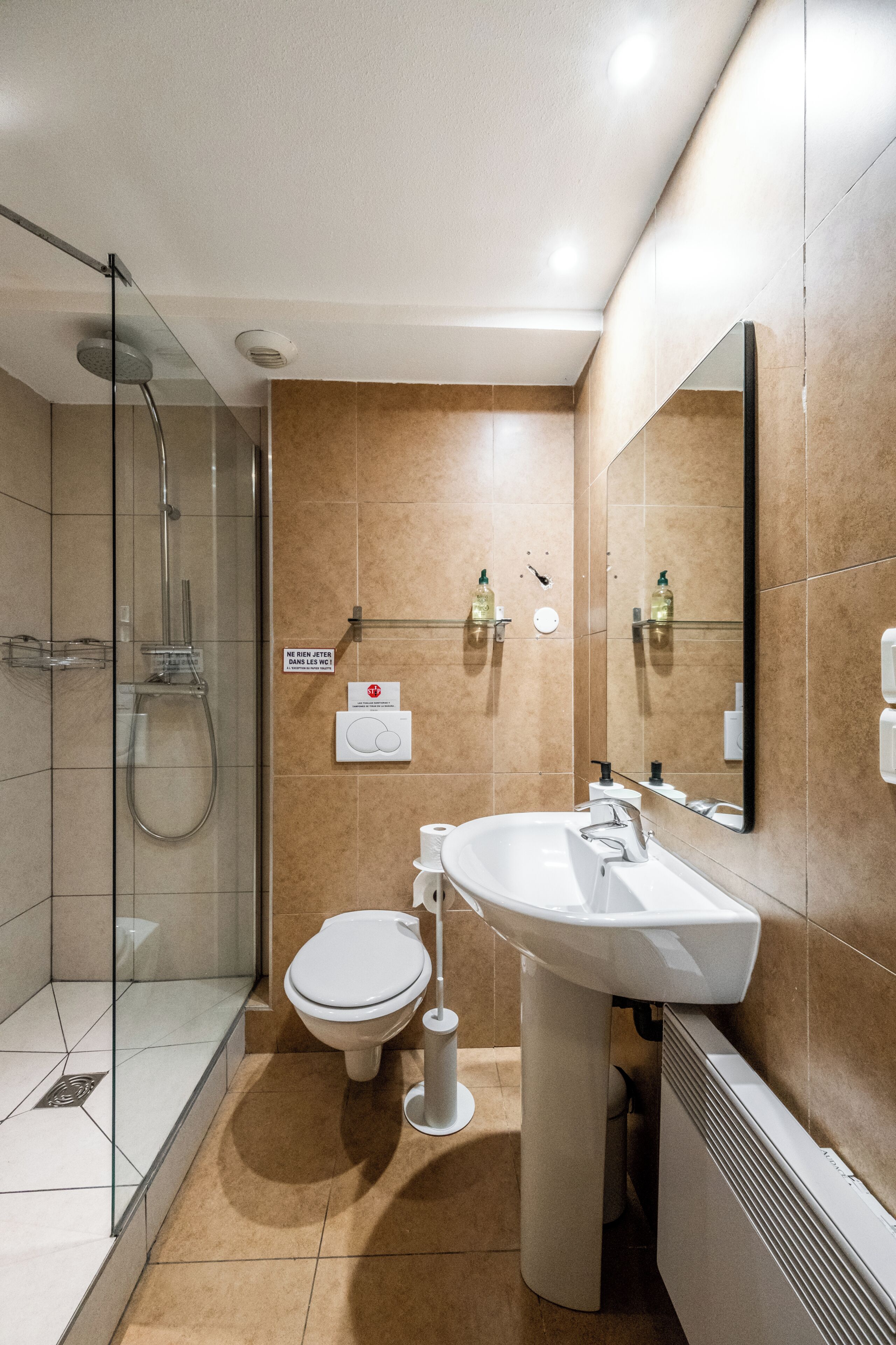 Ein modernes Badezimmer mit Duschkabine aus Glas, einem weißen Waschbecken und einer Toilette.