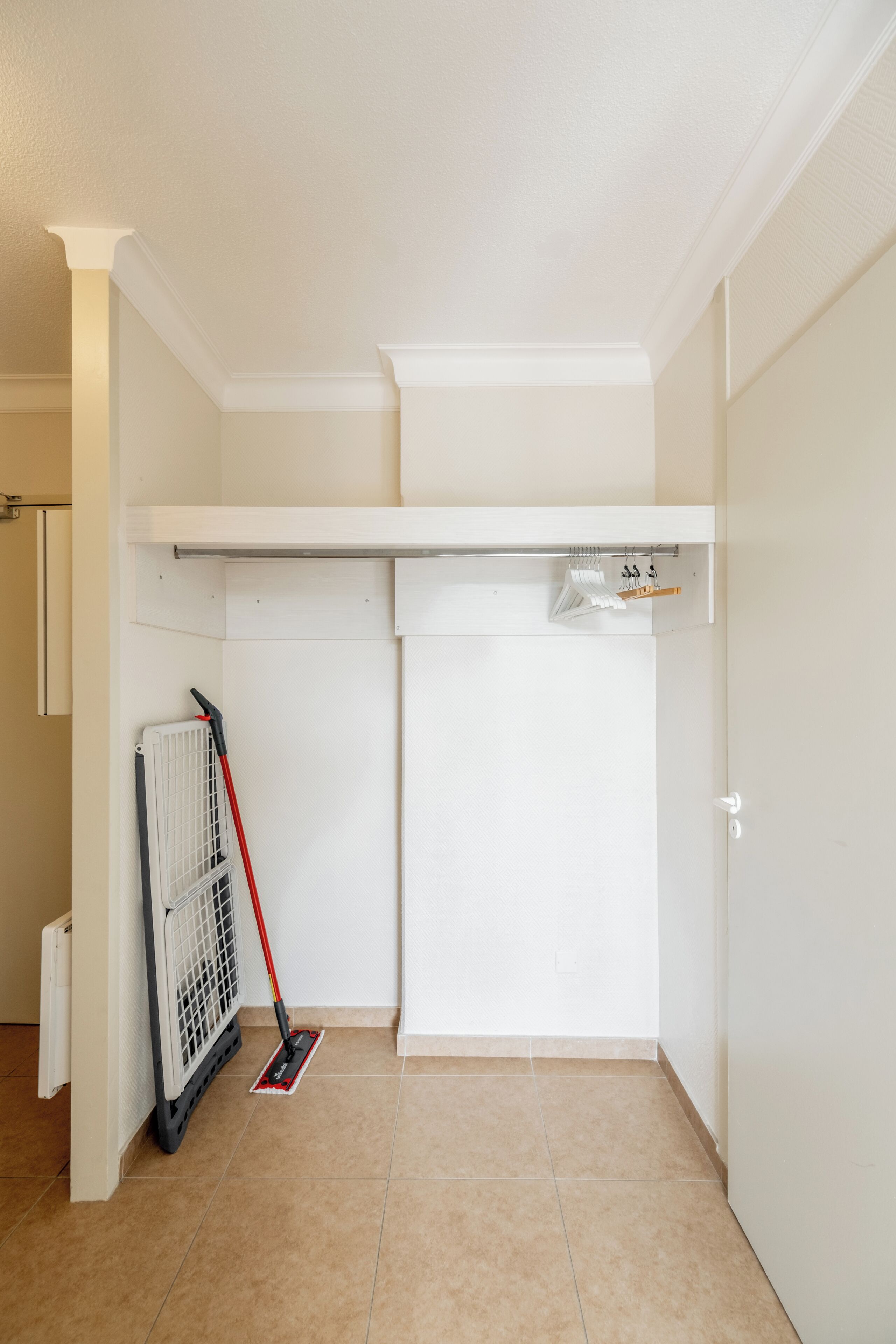 Une pièce avec un radiateur blanc, une serpillière et un étendoir à linge.