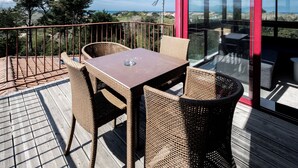 A wooden deck with wicker furniture, a table, and a glass enclosure with a red frame. - Résidence Château d'Acotz (Saint-Jean-de-Luz)