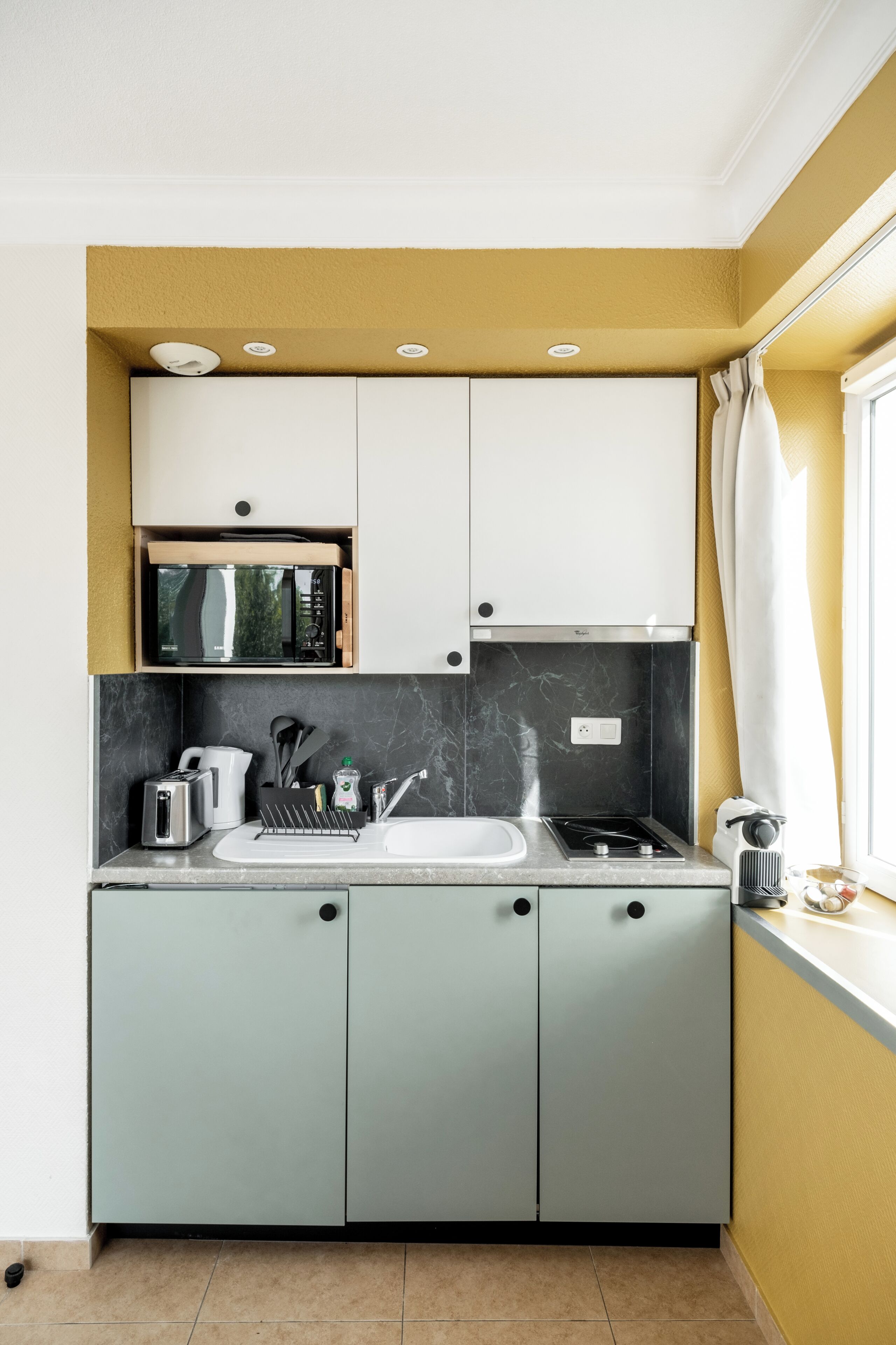 A compact kitchen with a microwave, toaster, sink, and stove.