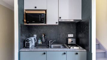 Una cocina compacta con microondas, tostadora y lavabo.