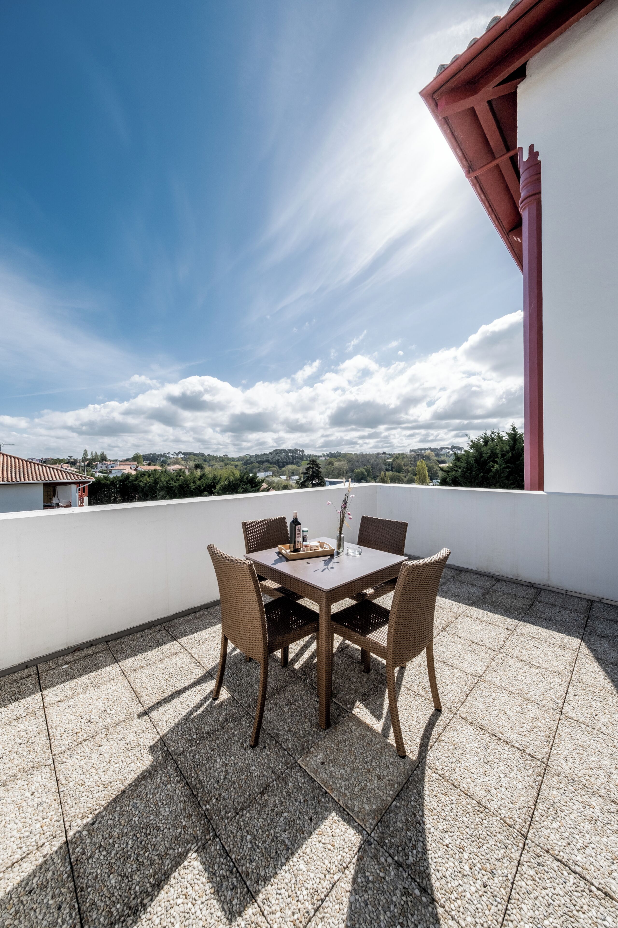 Une terrasse avec une table et des chaises, une colonne rouge et une vue sur le paysage.