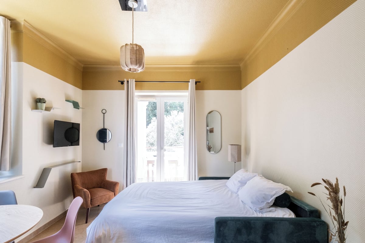 Un dormitorio moderno con cama, escritorio, silla, mesita de noche y espejo.