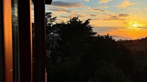 A sunset view from a window overlooking a landscape with trees and a distant horizon. - Résidence Château d'Acotz (Saint-Jean-de-Luz)