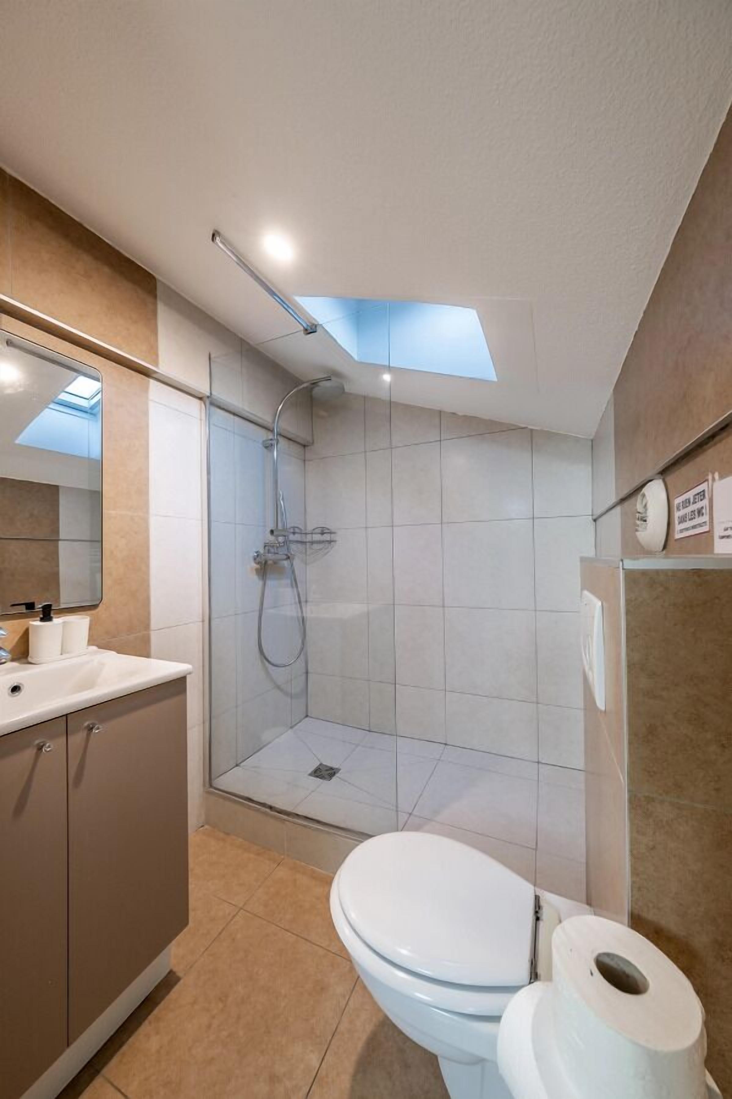 A modern bathroom with a shower, toilet, and sink.