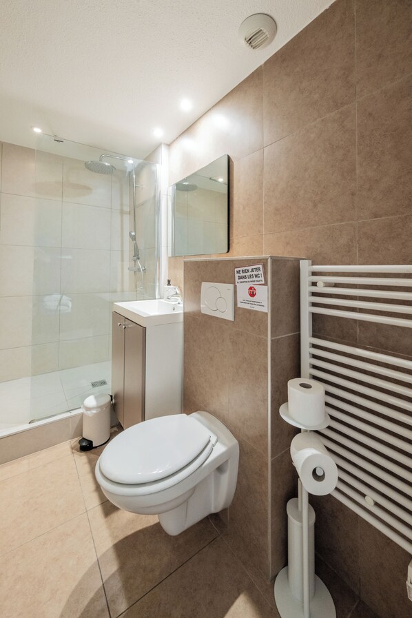 Une salle de bain moderne équipée d’une douche, de toilettes, d’un lavabo et d’un porte-serviettes.