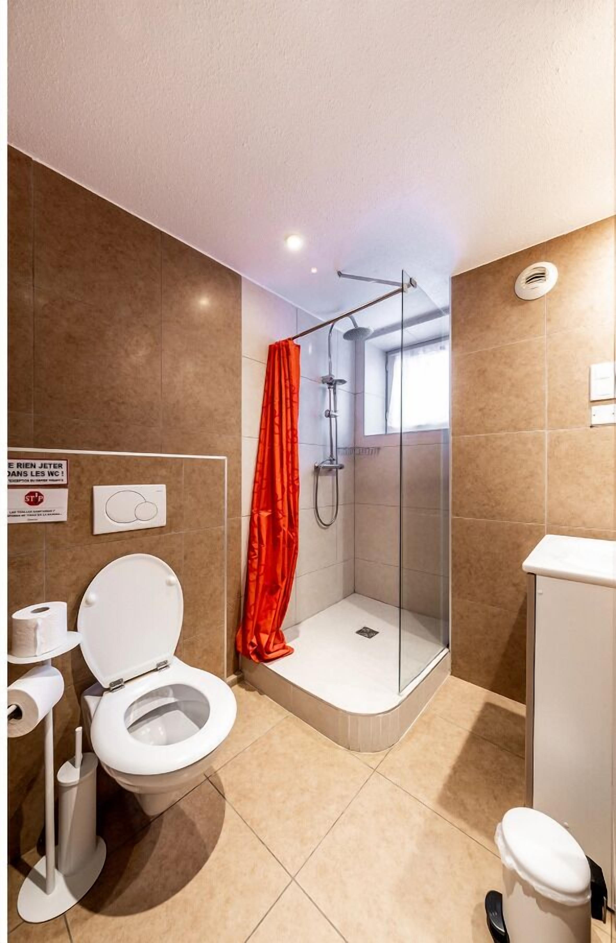 Een moderne badkamer met douche, toilet en wastafel.
