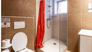 Een moderne badkamer met douche, toilet en wastafel.