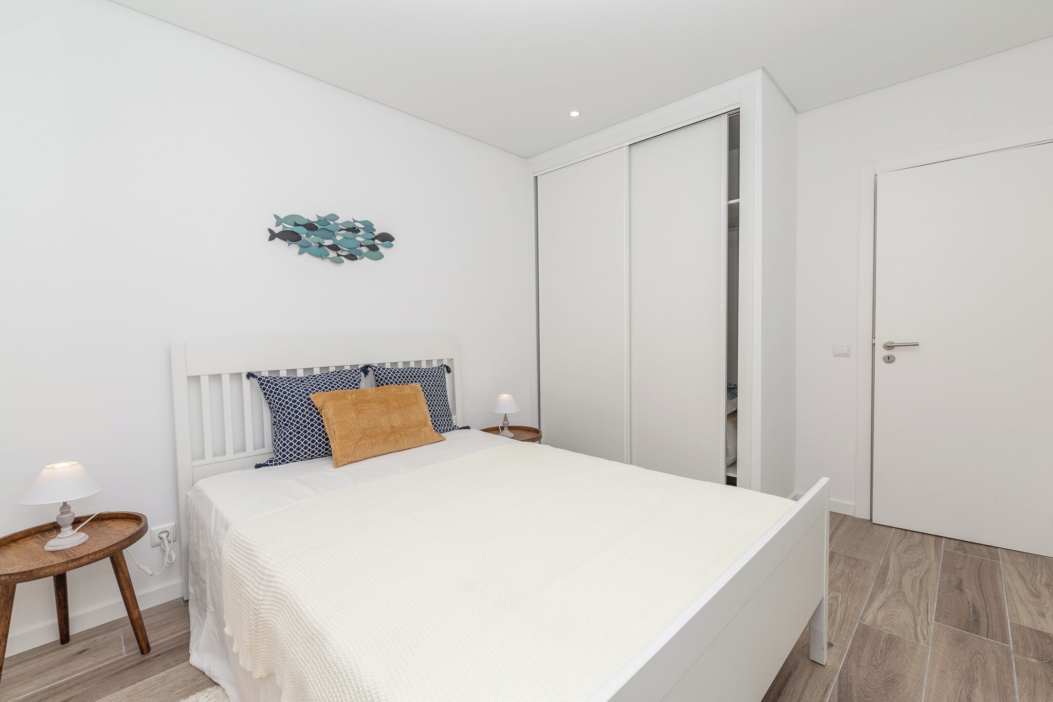 A bedroom with a bed, bedside tables, a wardrobe, and a decorative wall piece.